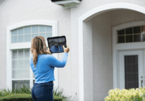 Woman photographing house exterior with tablet